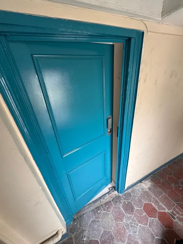 Porte palière bleue rénovée avec plaque de serrure neuve